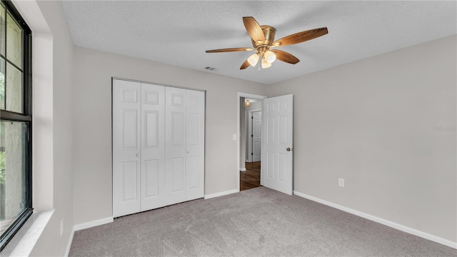 unfurnished bedroom with carpet, a closet, a textured ceiling, and baseboards