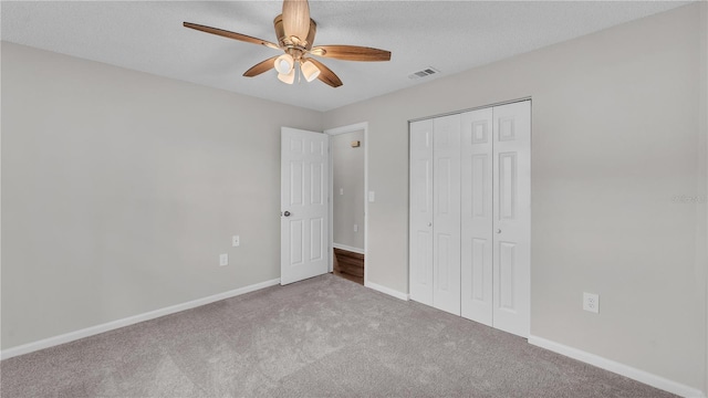 unfurnished bedroom featuring visible vents, baseboards, a textured ceiling, carpet flooring, and a closet