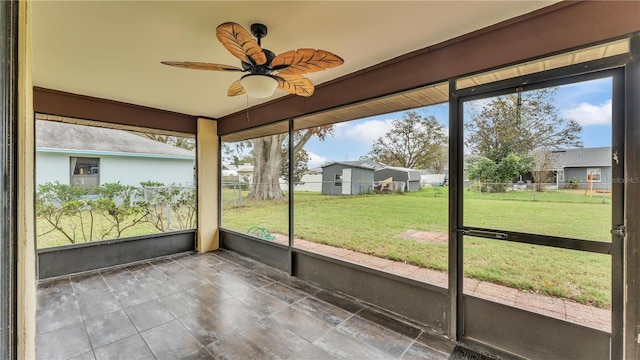 unfurnished sunroom featuring a residential view and a ceiling fan