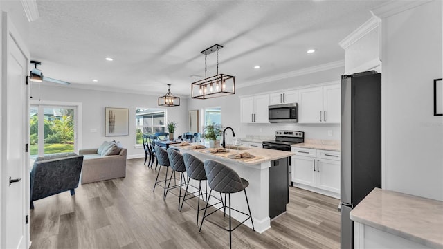 kitchen featuring white cabinets, open floor plan, a kitchen breakfast bar, appliances with stainless steel finishes, and light wood finished floors