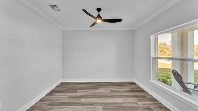 empty room featuring ornamental molding, visible vents, baseboards, and wood finished floors