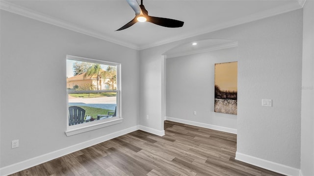 spare room with ceiling fan, baseboards, wood finished floors, and ornamental molding