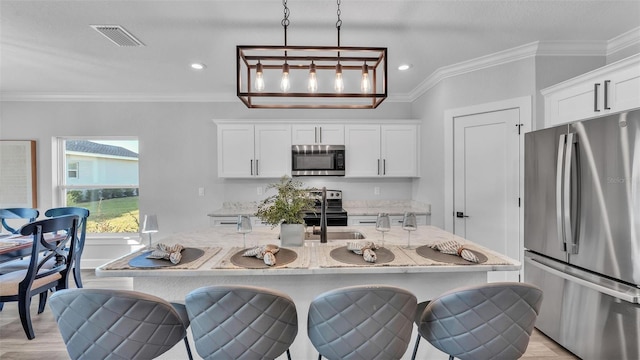 kitchen featuring stainless steel appliances, ornamental molding, and light stone countertops