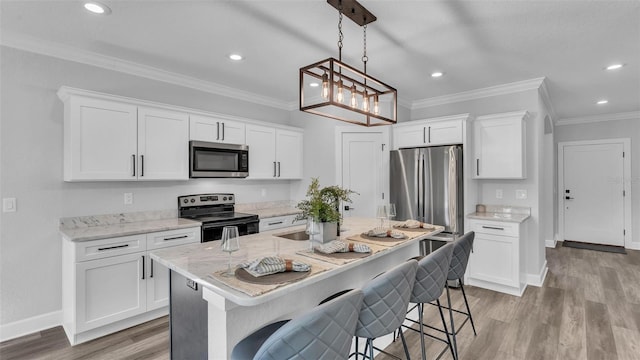 kitchen with stainless steel appliances, a sink, ornamental molding, light wood-type flooring, and a kitchen bar