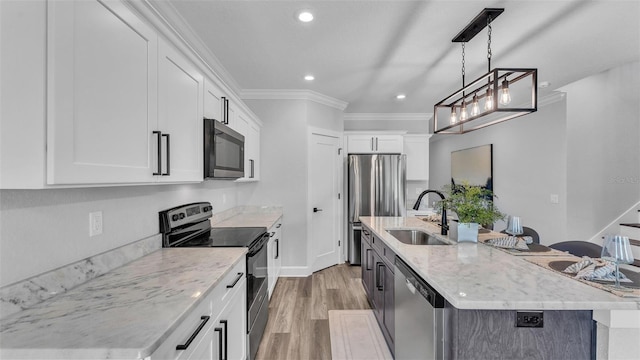 kitchen with light wood-style flooring, a sink, appliances with stainless steel finishes, an island with sink, and crown molding