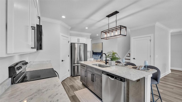 kitchen featuring stainless steel appliances, a breakfast bar, a sink, white cabinetry, and light wood finished floors