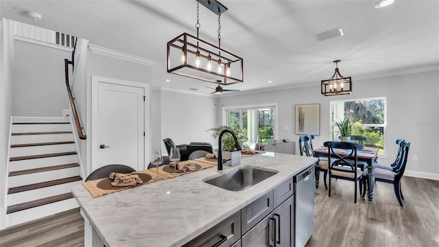 kitchen with light wood finished floors, dishwasher, ornamental molding, decorative light fixtures, and a sink