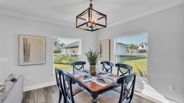 dining area with ornamental molding, an inviting chandelier, baseboards, and wood finished floors