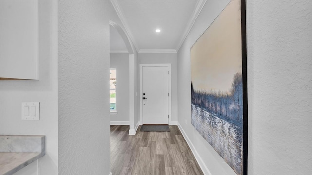 foyer featuring baseboards, ornamental molding, wood finished floors, and a textured wall