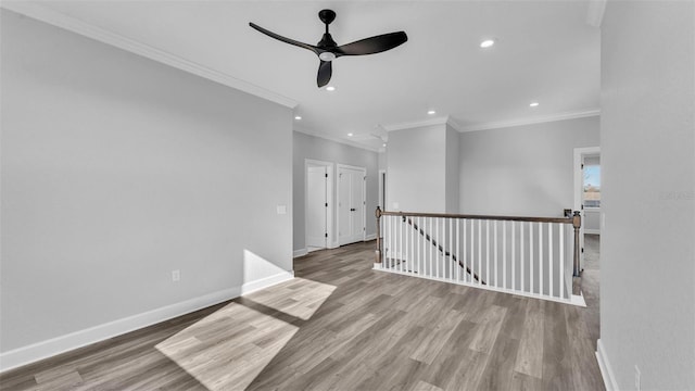 spare room with crown molding, recessed lighting, wood finished floors, and baseboards