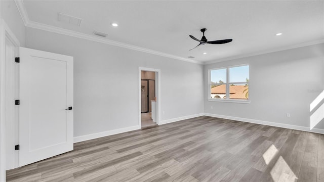 spare room with crown molding, light wood-style flooring, and baseboards