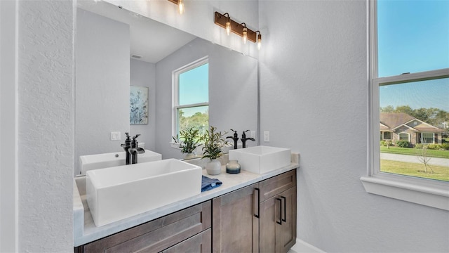 full bathroom featuring a textured wall, a sink, and double vanity