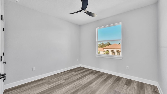 spare room featuring ceiling fan, baseboards, and wood finished floors