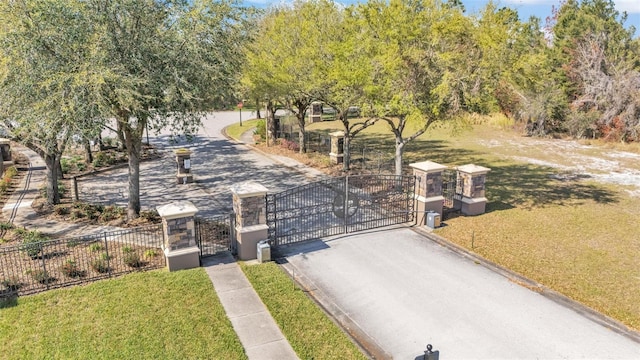 view of street with a gate, a gated entry, and curbs