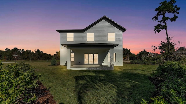 back of house with a patio area, a lawn, and stucco siding