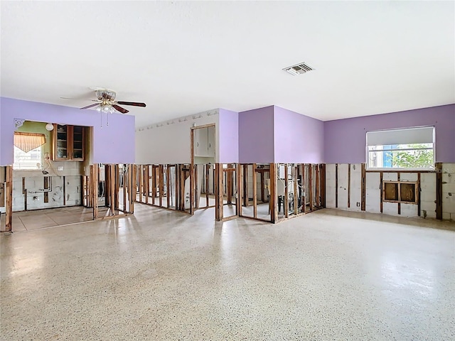 interior space with visible vents, plenty of natural light, speckled floor, and a ceiling fan