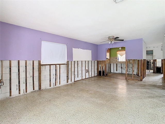 unfurnished living room featuring speckled floor and ceiling fan