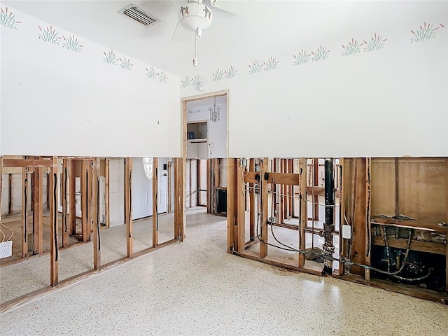 interior space with speckled floor, visible vents, and ceiling fan