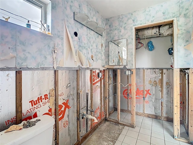 interior space featuring tile patterned flooring, toilet, and wallpapered walls