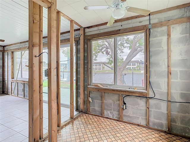 misc room with tile patterned floors, a water view, and ceiling fan