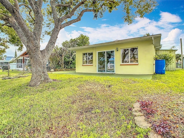 back of house featuring stucco siding, a yard, and fence