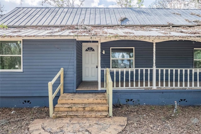 doorway to property with covered porch, metal roof, crawl space, and a standing seam roof