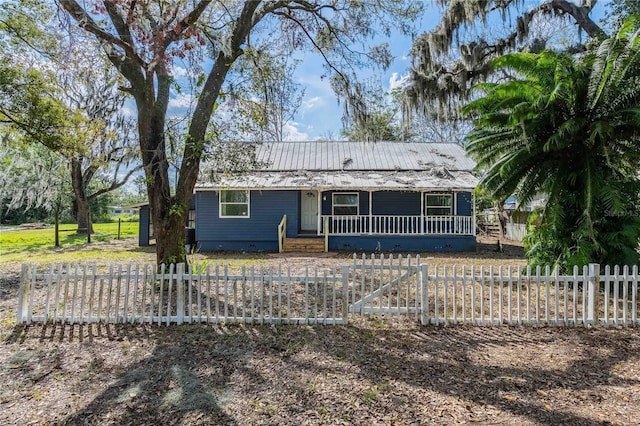 single story home with metal roof, a fenced front yard, and a porch