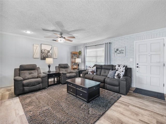 living room with ceiling fan, a textured ceiling, crown molding, and wood finished floors