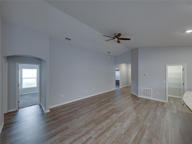 unfurnished living room with visible vents, arched walkways, light wood-style floors, and a ceiling fan