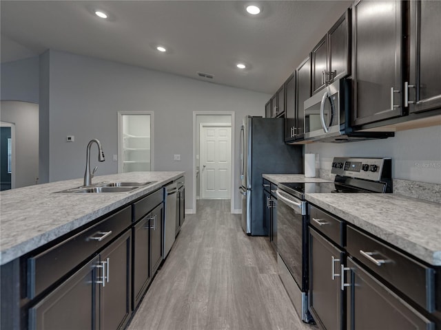 kitchen with visible vents, vaulted ceiling, arched walkways, stainless steel appliances, and a sink