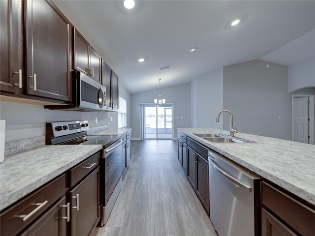 kitchen featuring dark brown cabinetry, light countertops, vaulted ceiling, stainless steel appliances, and a sink