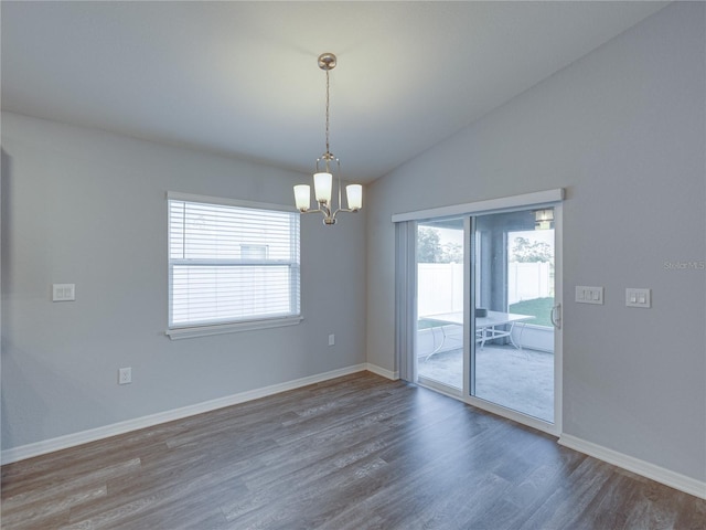 unfurnished room with lofted ceiling, wood finished floors, baseboards, and a chandelier