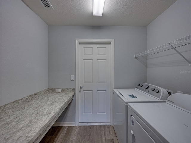 washroom featuring visible vents, dark wood finished floors, laundry area, a textured ceiling, and washer and dryer