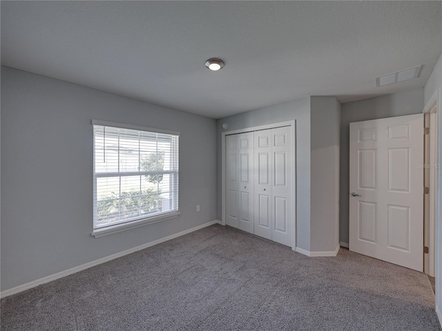 unfurnished bedroom with carpet, visible vents, a closet, and baseboards