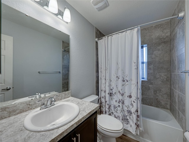 full bathroom featuring visible vents, toilet, a textured wall, shower / bath combination with curtain, and vanity