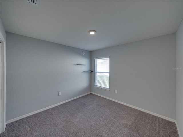 carpeted spare room with visible vents and baseboards