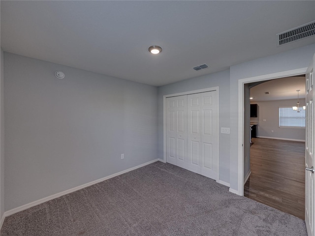 unfurnished bedroom featuring a closet, visible vents, baseboards, and dark colored carpet