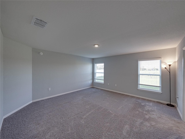 unfurnished room featuring visible vents, carpet floors, and baseboards