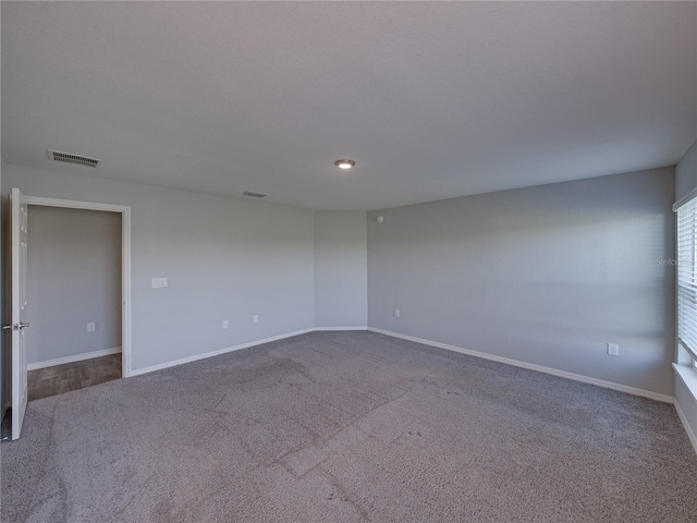 carpeted spare room with visible vents and baseboards