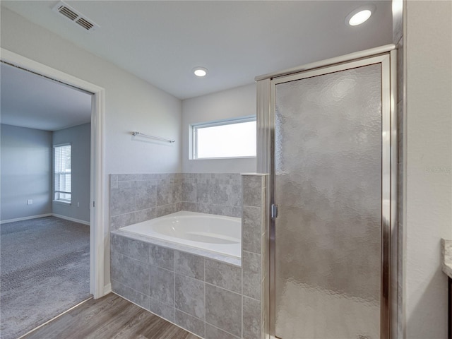 bathroom with a garden tub, a healthy amount of sunlight, visible vents, and a shower stall