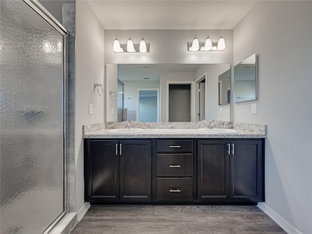 bathroom featuring a stall shower, wood finished floors, and a sink