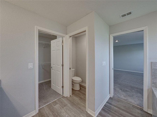 bathroom featuring toilet, wood finished floors, visible vents, and baseboards