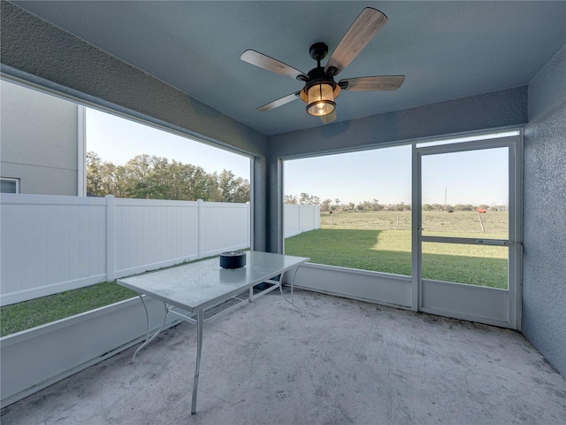 unfurnished sunroom with plenty of natural light and a ceiling fan