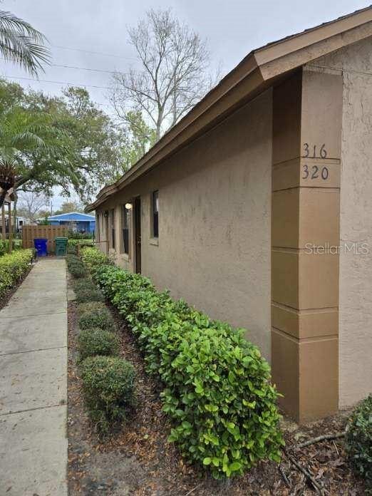 view of side of home featuring fence and stucco siding