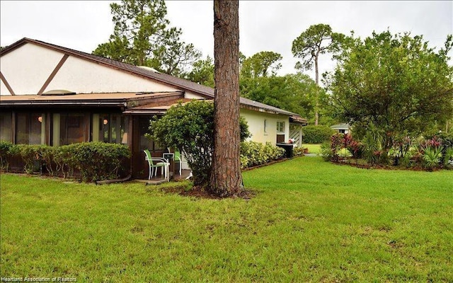 view of side of home with a lawn and stucco siding