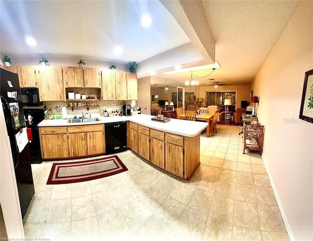 kitchen featuring tasteful backsplash, light countertops, a sink, a peninsula, and black appliances