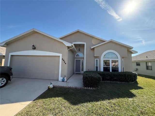 ranch-style house with a garage, driveway, a front lawn, and stucco siding