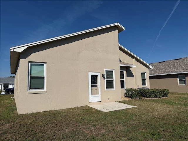 rear view of house with a lawn and stucco siding