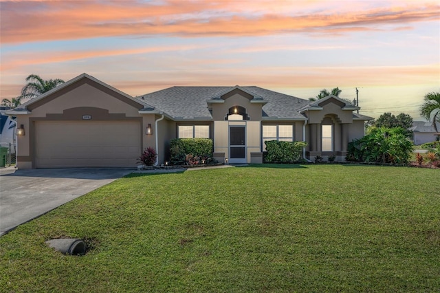 single story home featuring a garage, a yard, concrete driveway, roof with shingles, and stucco siding