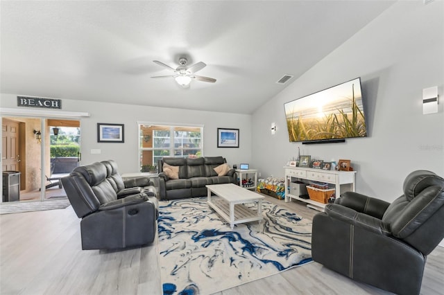 living area with a wealth of natural light, visible vents, vaulted ceiling, and wood finished floors